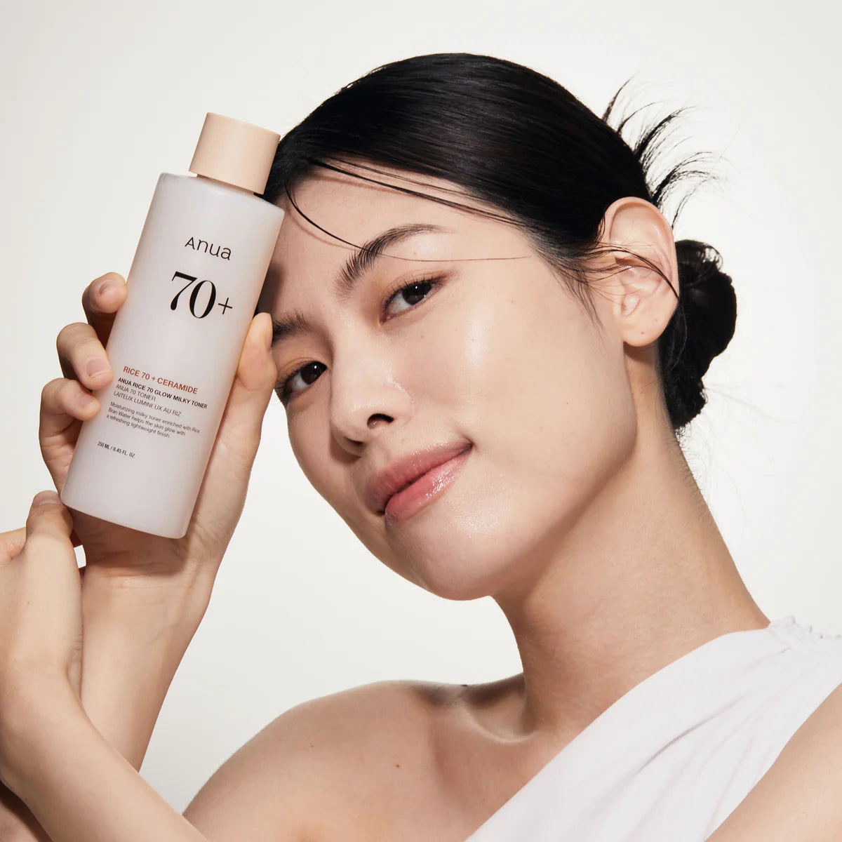 Woman holding a skincare product with a neutral background