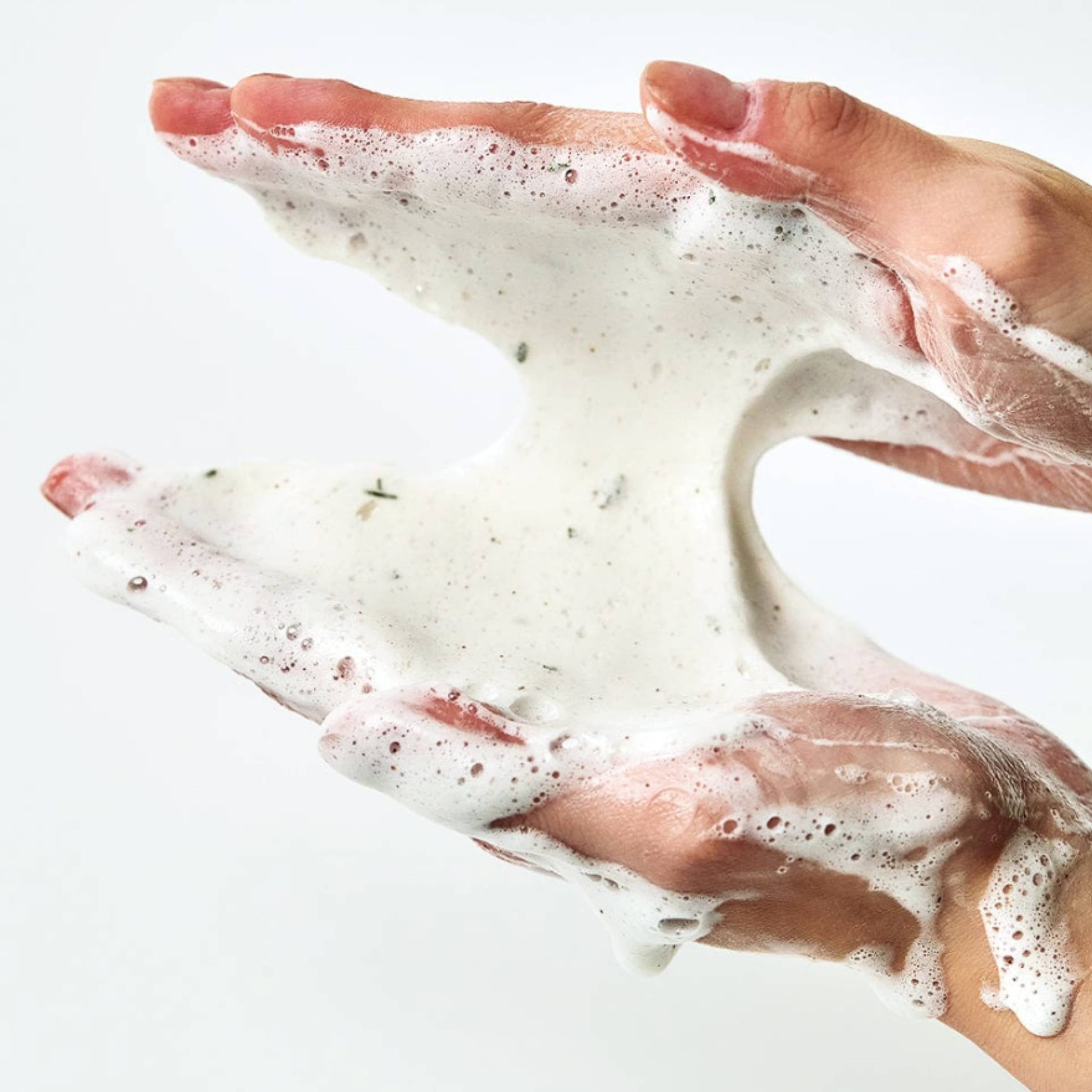 Close-up of hands with soap suds on a white background