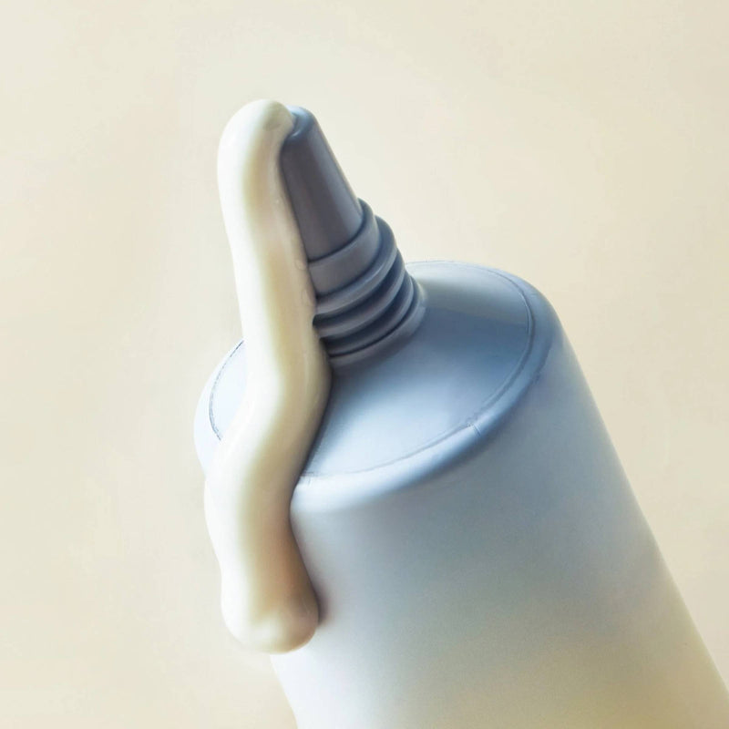 Close-up of a bottle with a nozzle on a beige background