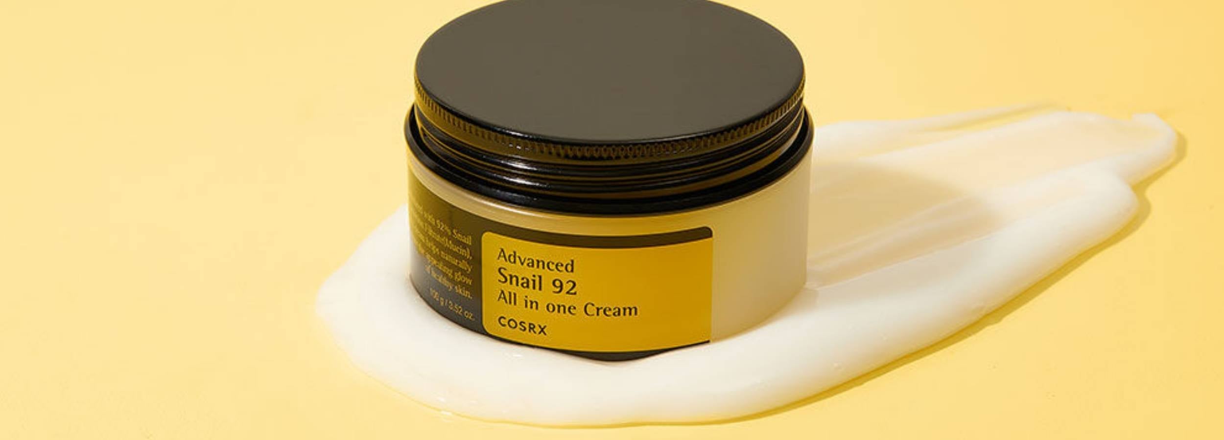 Jar of COSRX snail cream with a black lid on a yellow background