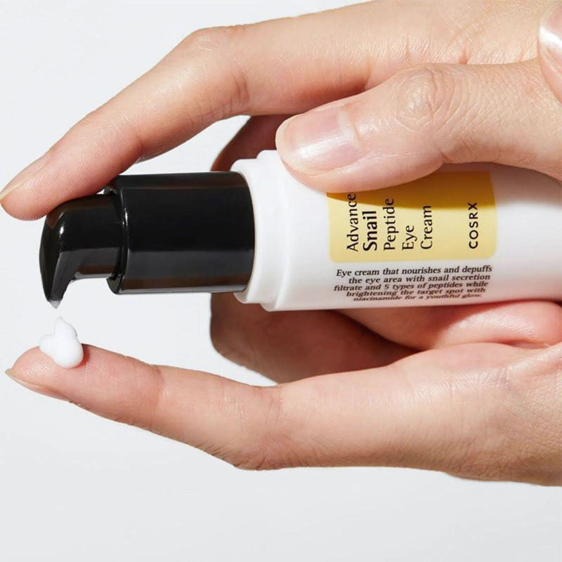 CosRX eye cream being applied to a person's finger on a white background