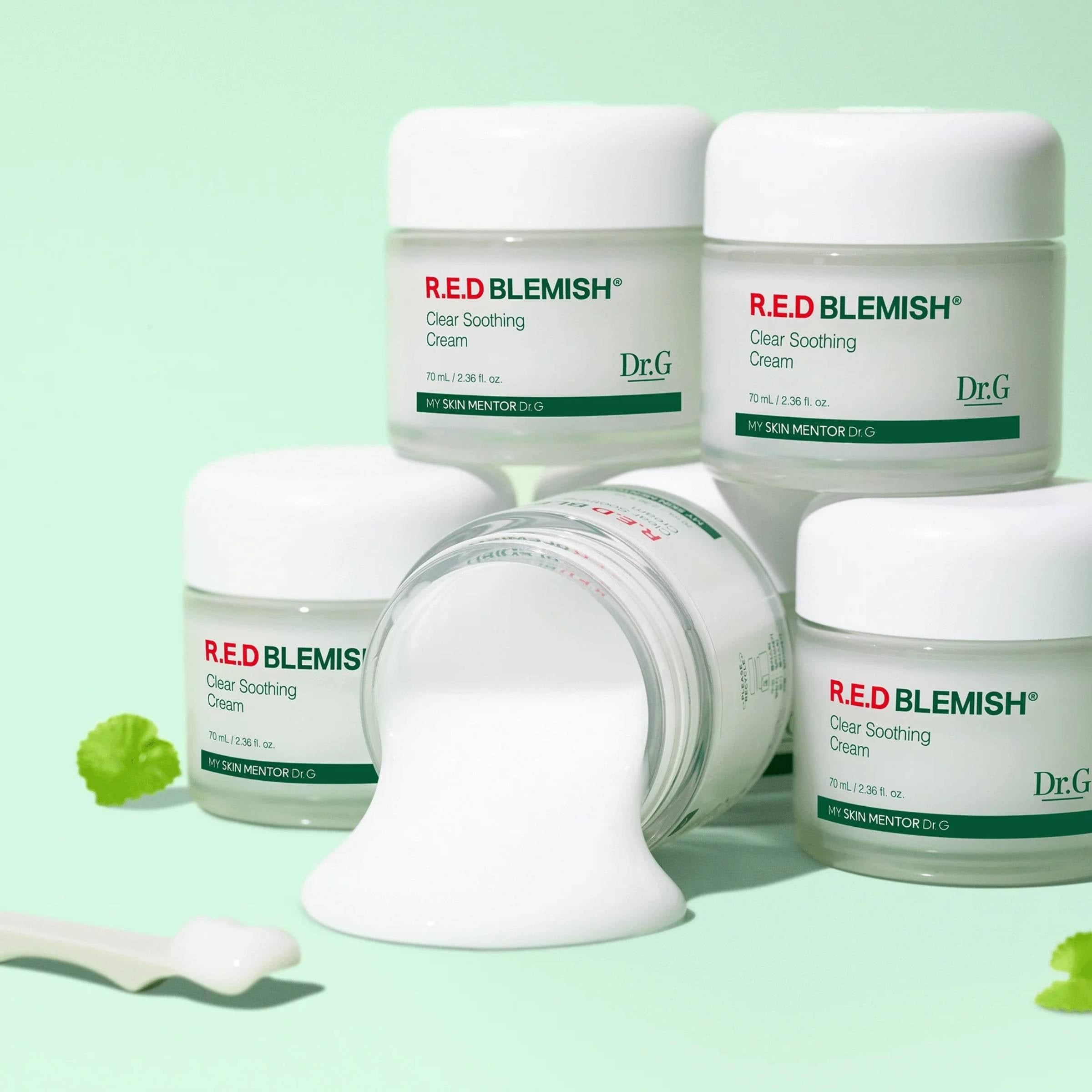Multiple jars of Dr.G Red Blemish Clear Soothing Cream on a light green background