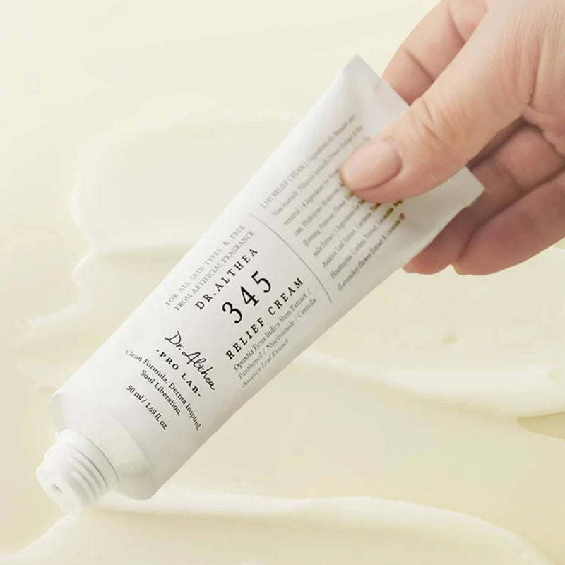 Hand holding a tube of Dr. Althea 345 Relief Cream against a beige background