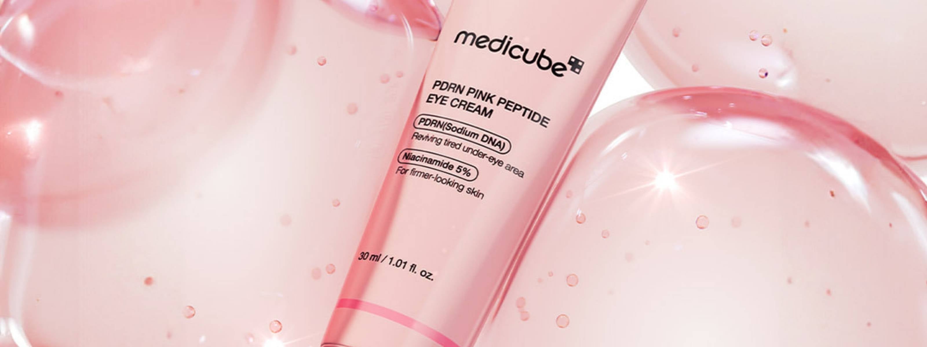 Medicube pink eye cream bottle on a pink background