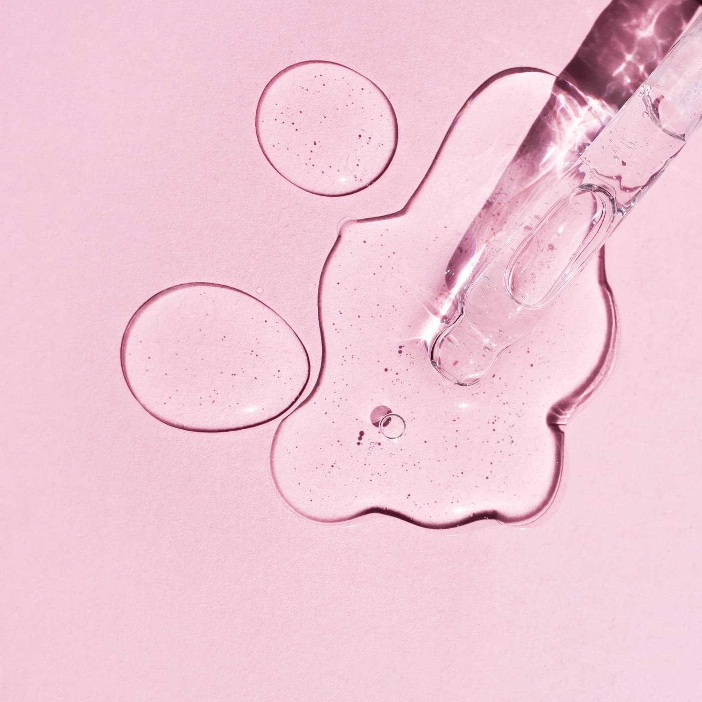 Glass dropper with pink ampoule on a pink background