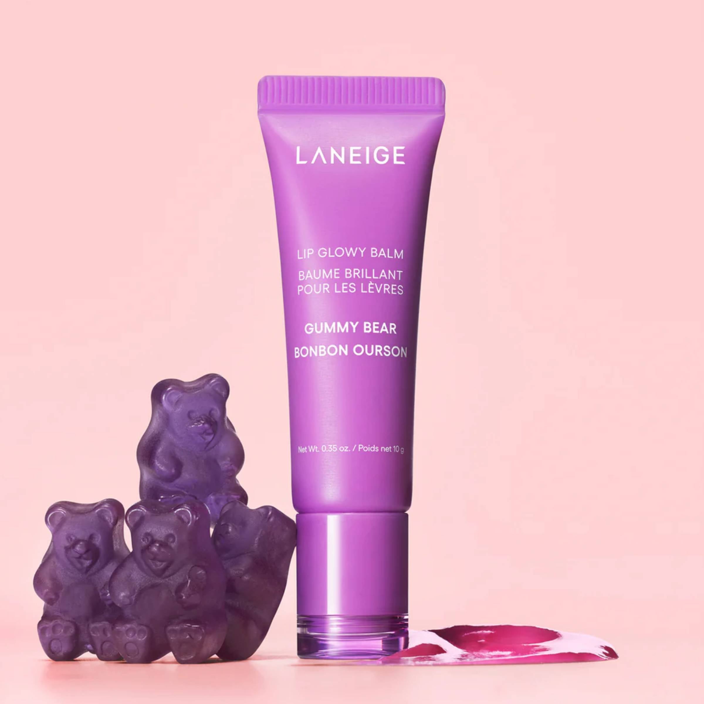 Purple Laneige lip balm with gummy bear candies on a pink background