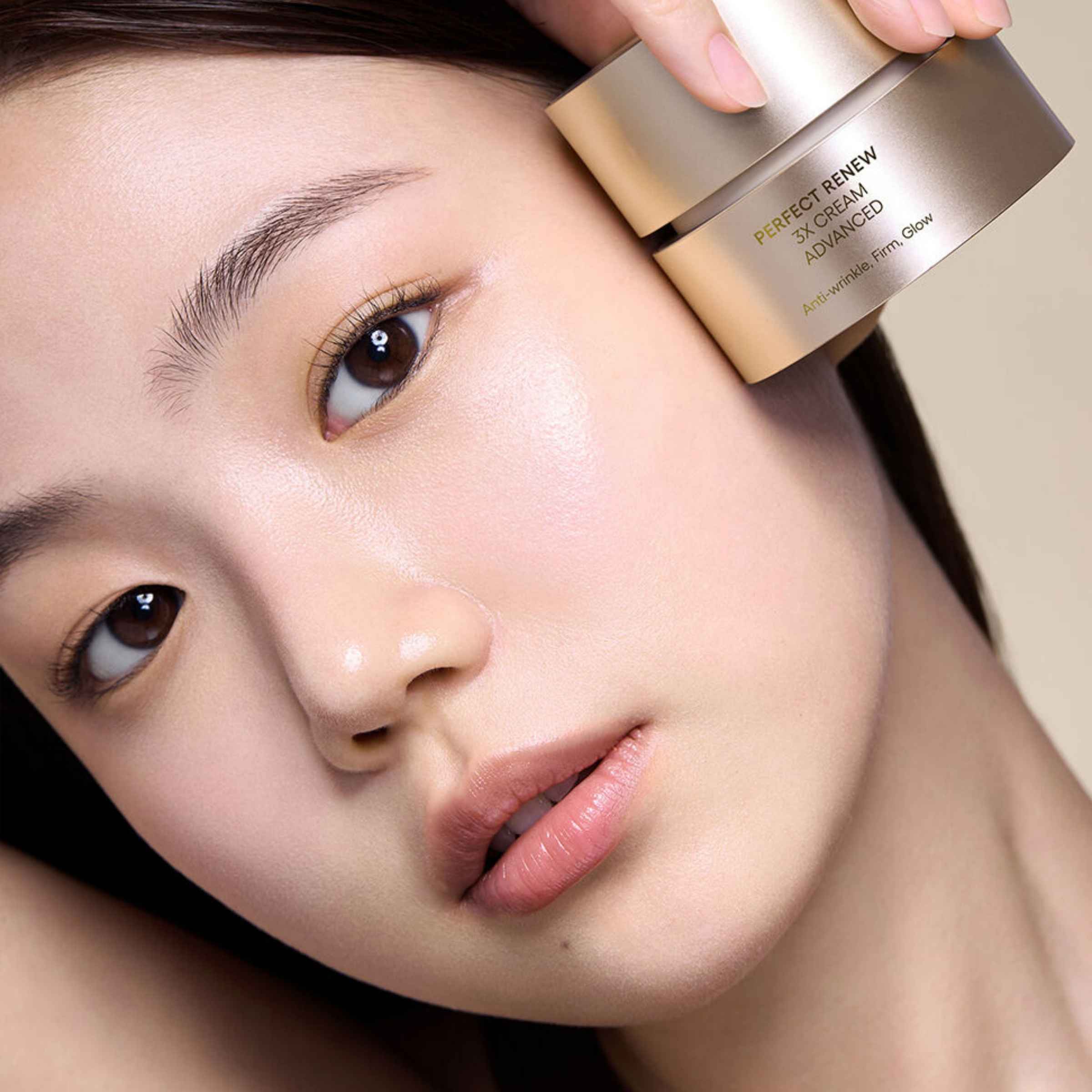 Person applying a skincare product to their face with a focus on the product packaging.