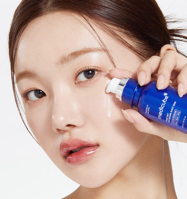 Woman applying a blue bottle of Medicube product to her face.