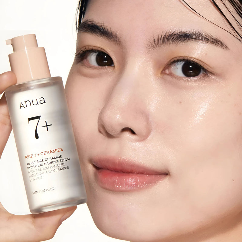 Person holding a skincare serum bottle labeled 'Anua' with a close-up of their face.