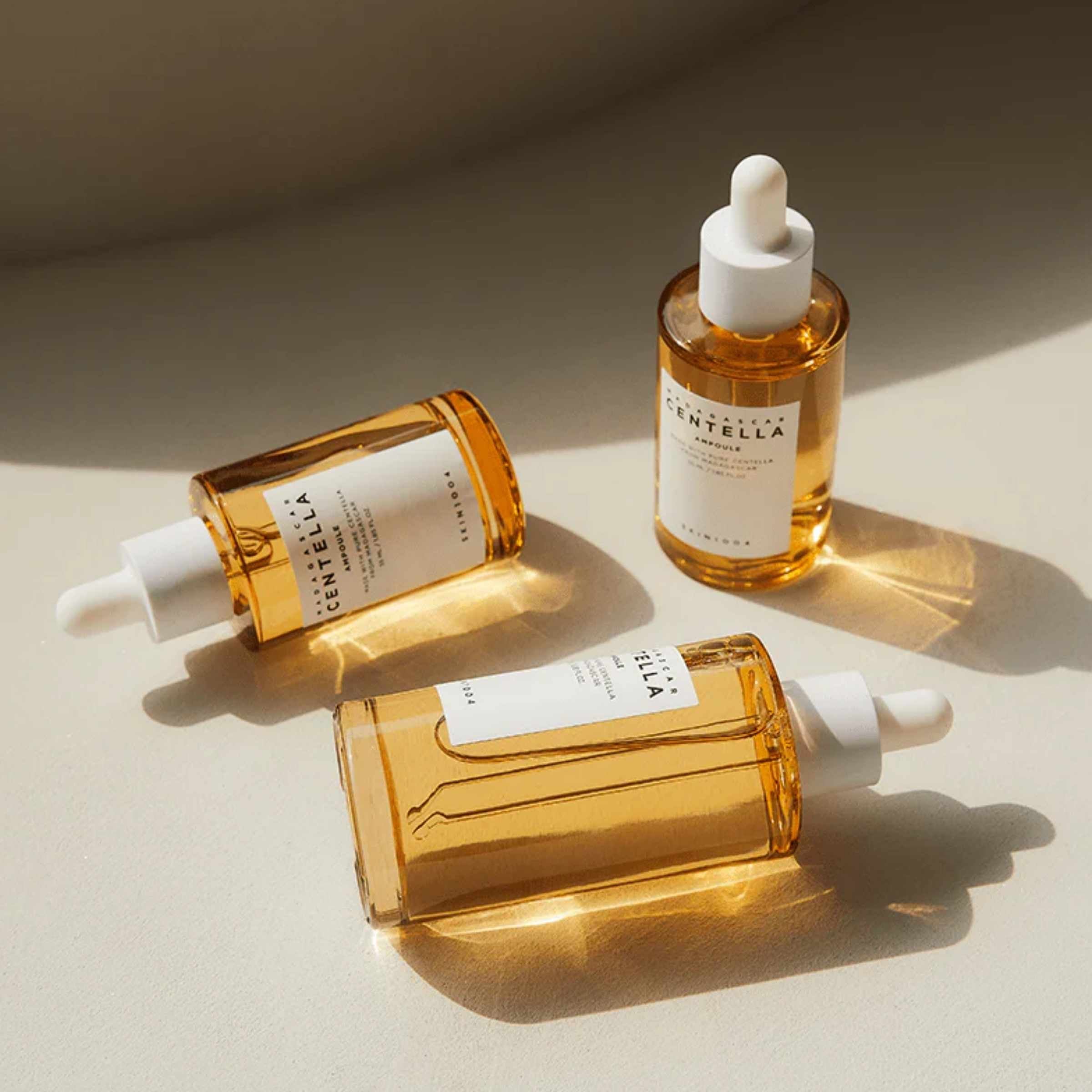 Three bottles of Centella serum on a beige background