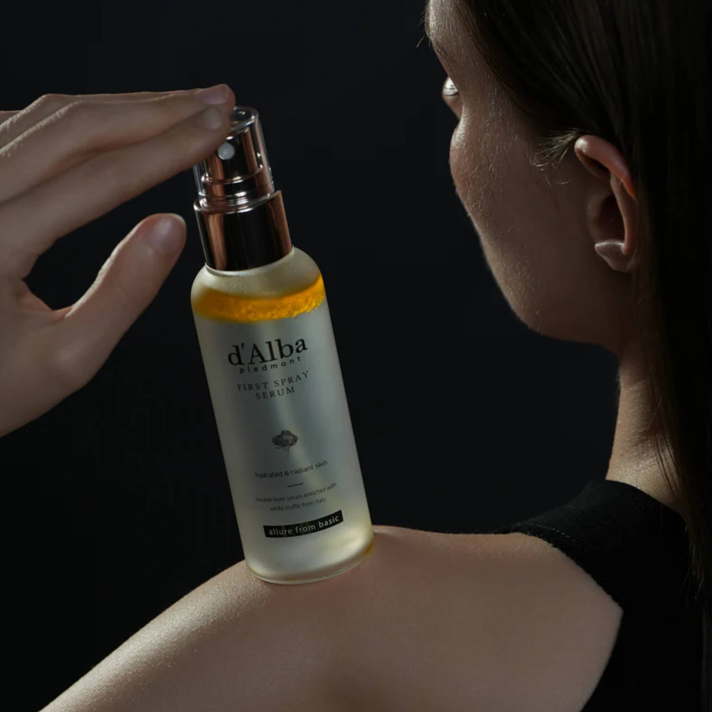 Person holding a bottle of d'Alba skincare product against a dark background