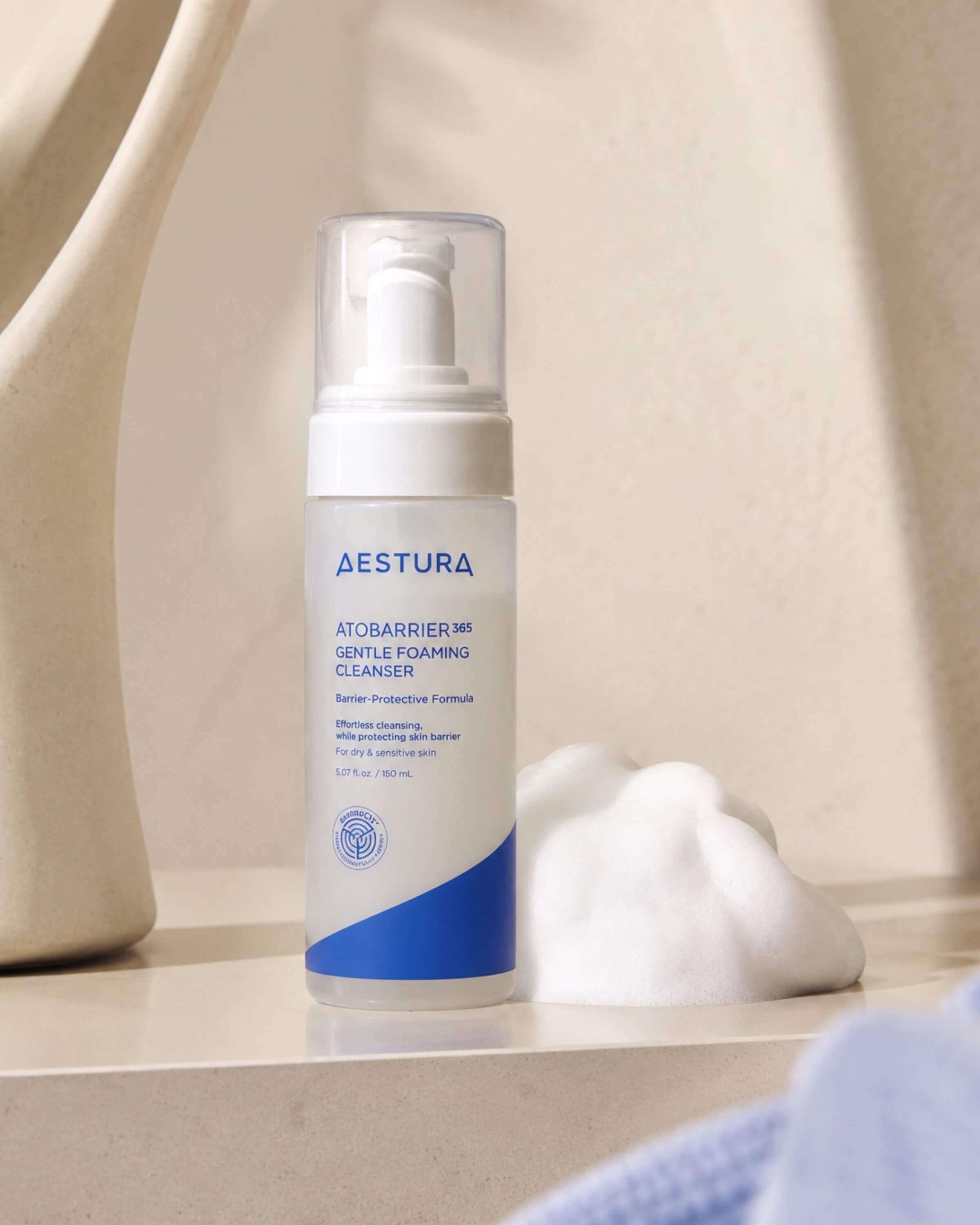 Aestura gentle foaming cleanser bottle on a bathroom shelf with a blurred background