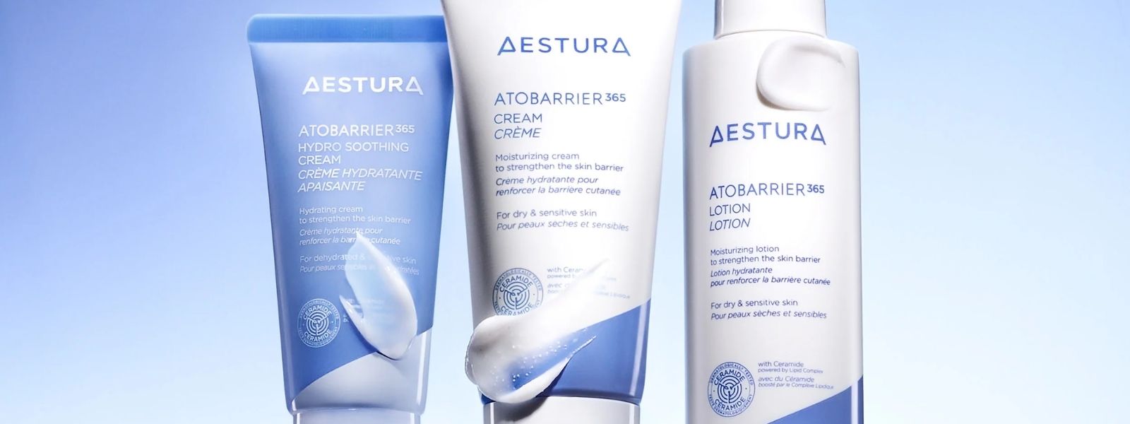 Aestura skincare products including cream, lotion, and cleanser on a light blue background