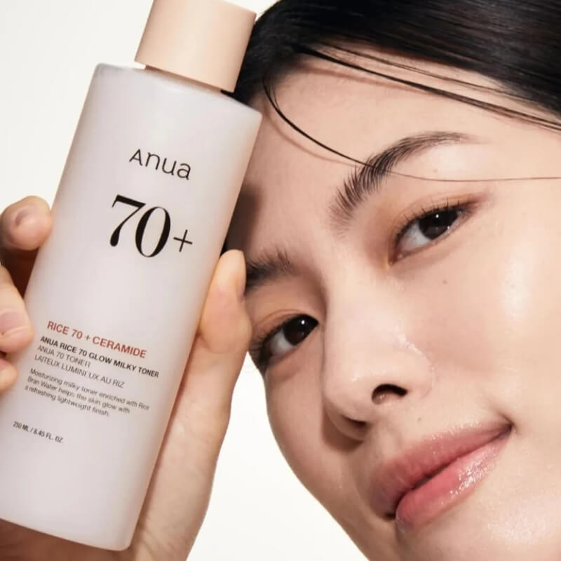Woman holding aANUA Rice 70 Glow Milky Toner with a close-up of their face