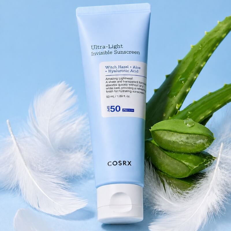 COSRX Ultra Light Invisible Sunscreen on a blue background surrounded by feathers and aloe vera