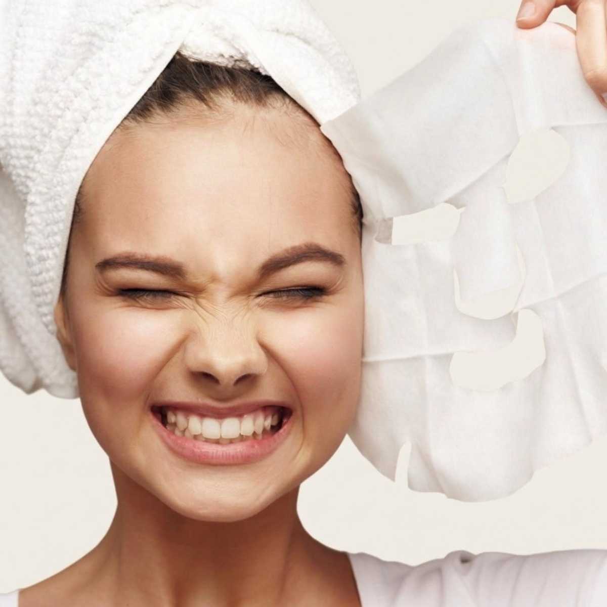 Close-up of a person applying korean face mask on a neutral background