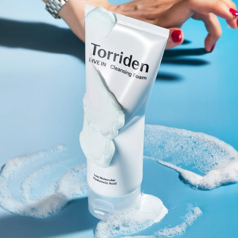 Torriden Dive In Hyaluronic Acid Cleansing Foam with foamy texture on a blue background