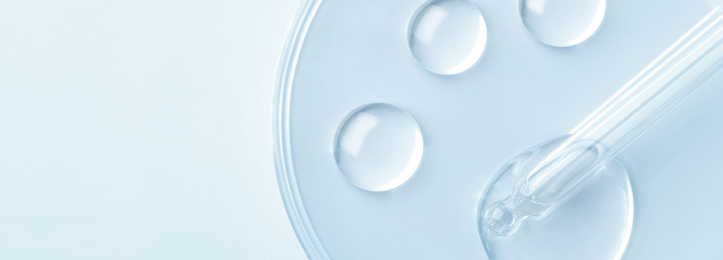 Clear dropper with liquid and bubbles on a light blue background