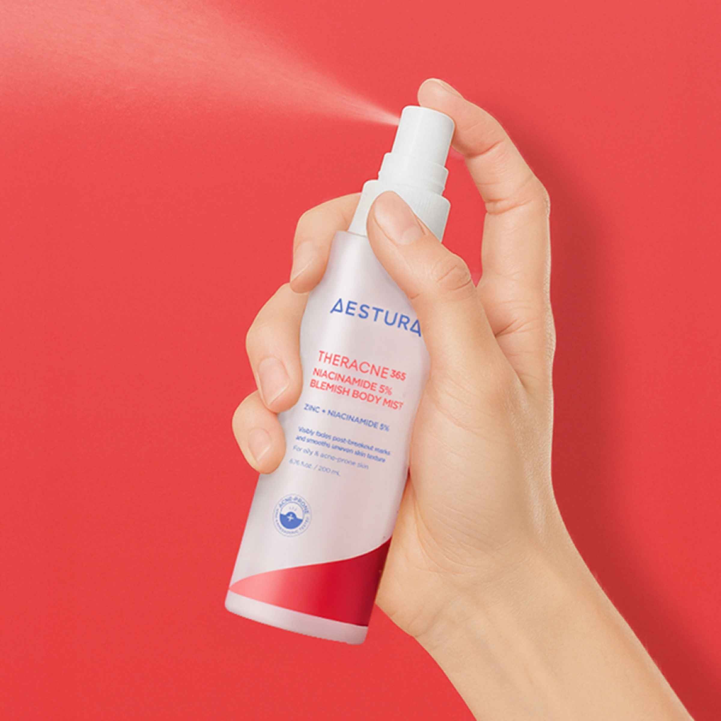 Hand holding a bottle of Aestura Thermaerum product against a red background
