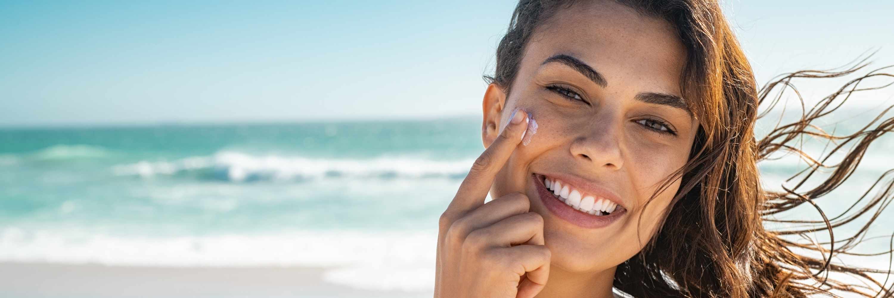 Woman applying sunscreen on her face at the beach