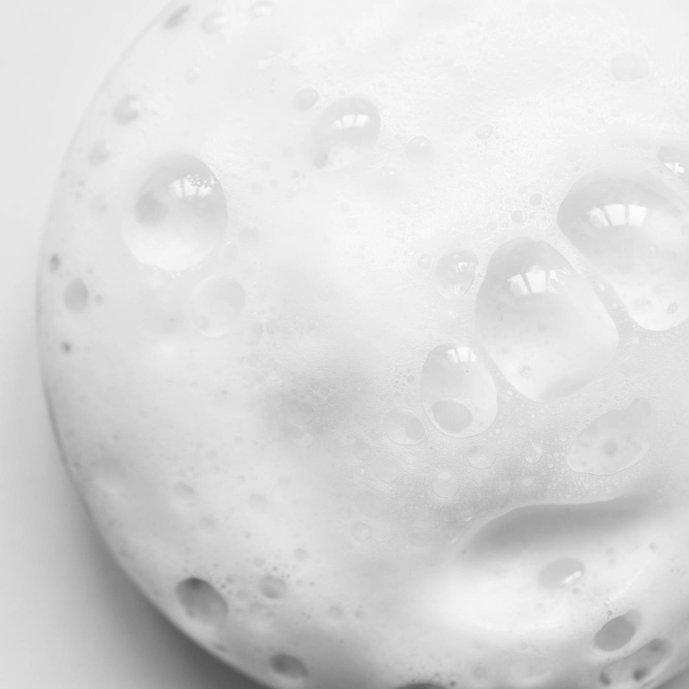 Close-up of cleansing foam with bubbles on a light grey background