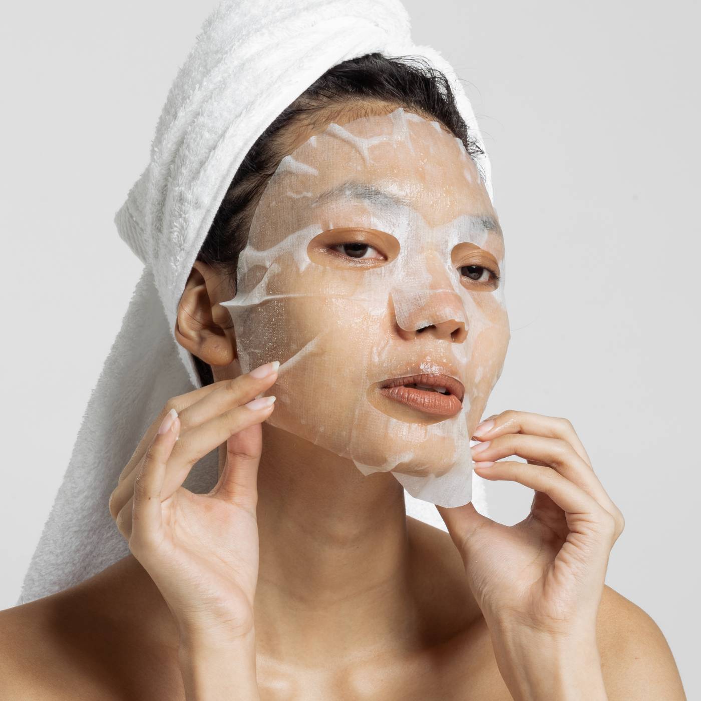 Close up of women applying a facial sheet mask