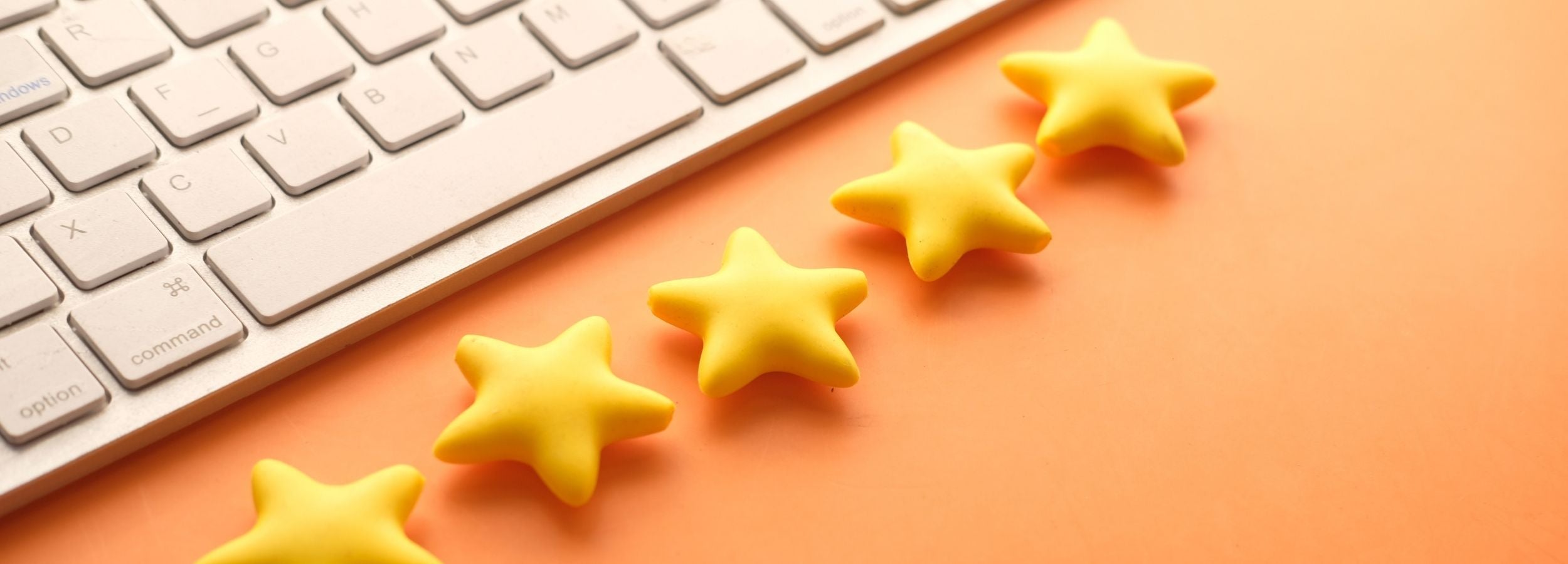Five yellow stars arranged on an orange surface with a white keyboard in the background.