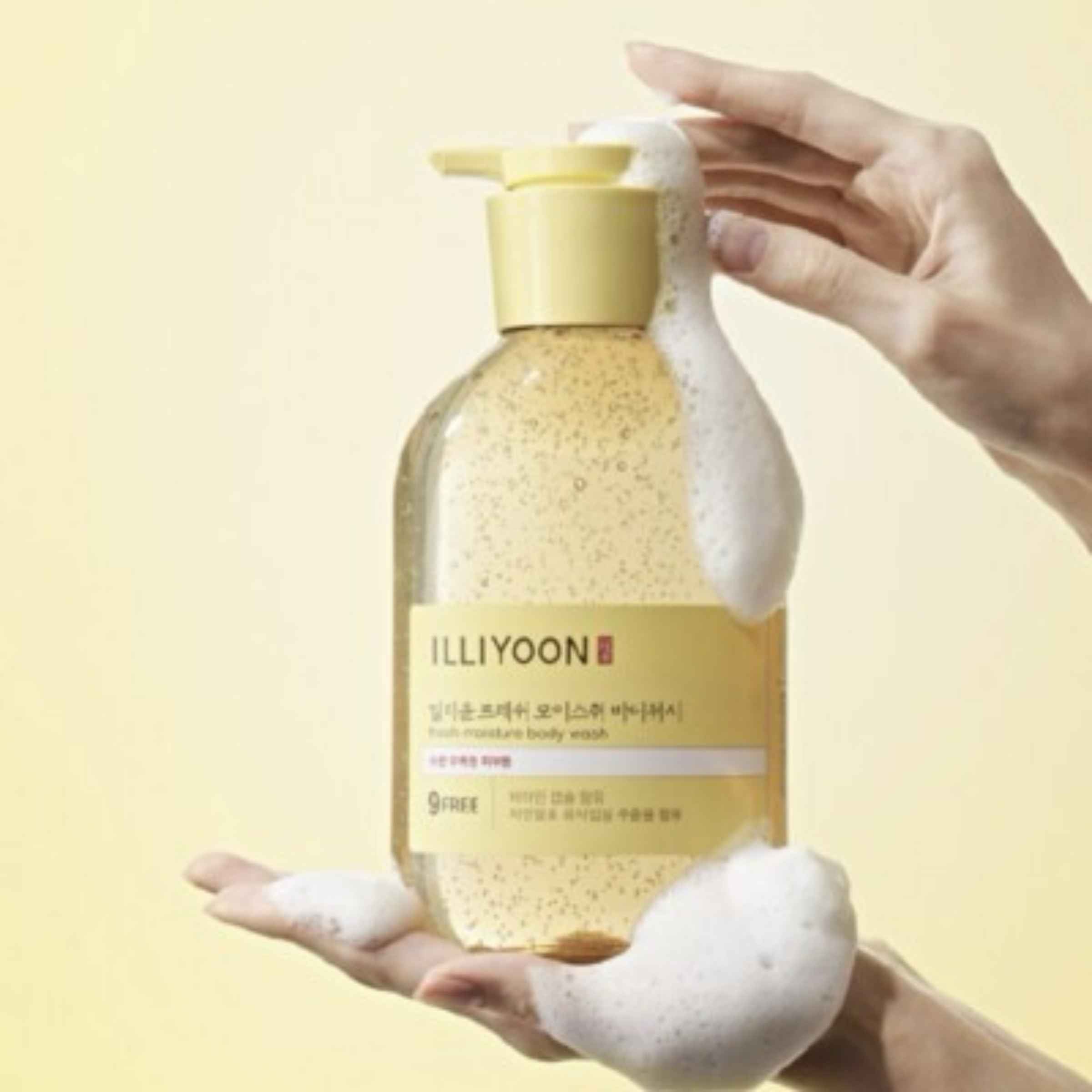 Hand holding a bottle of Illiyoon body wash with a yellow background