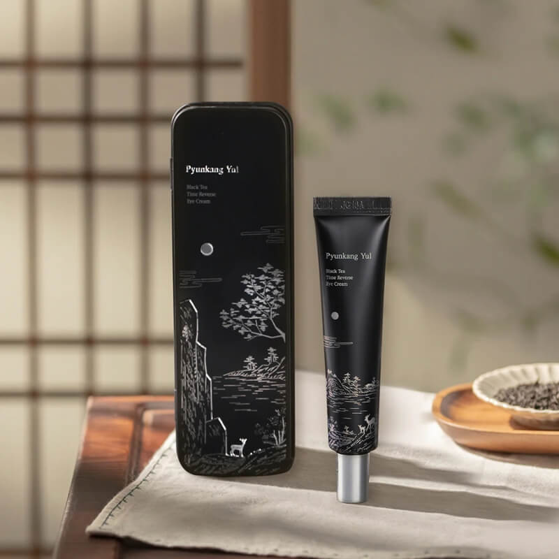 Pyunkang Yul Black Tea Time Reverse Eye Cream on a wooden table with a blurred background. 