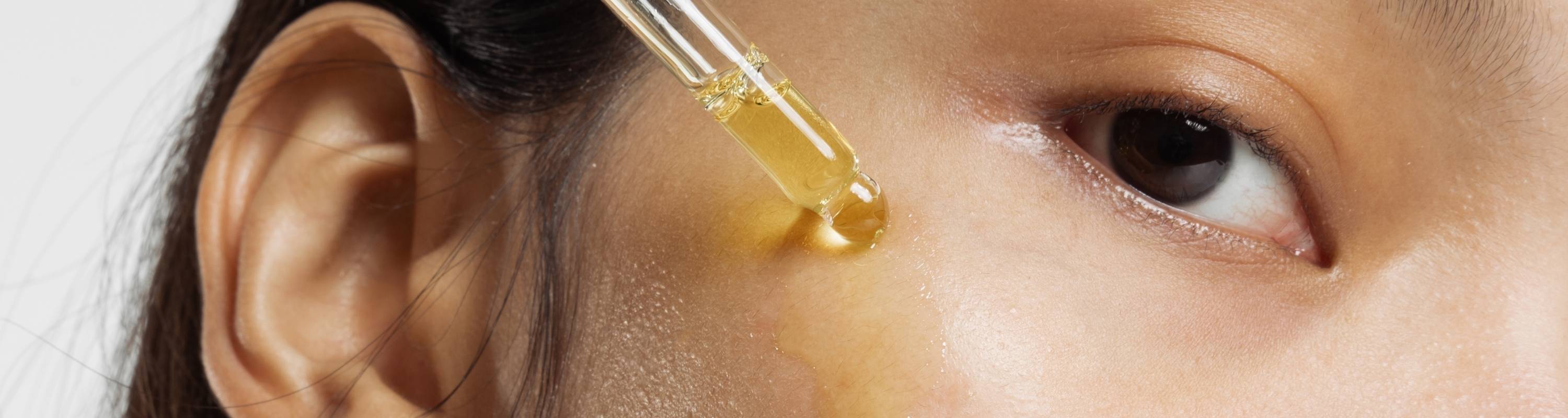 Close-up of a dropper applying serum to the eye area.