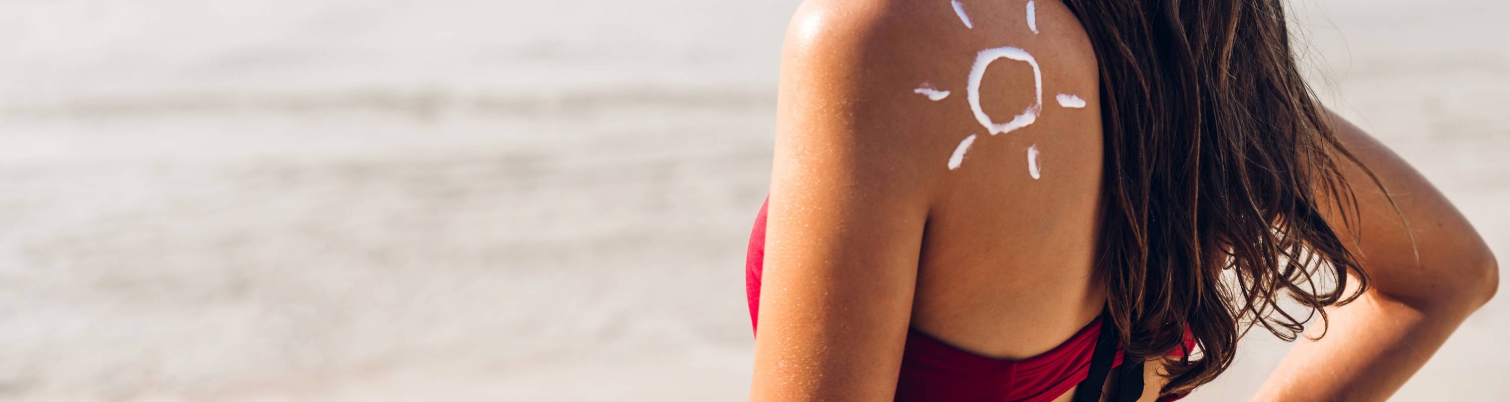 Person with a sun-shaped drawing on their back at the beach