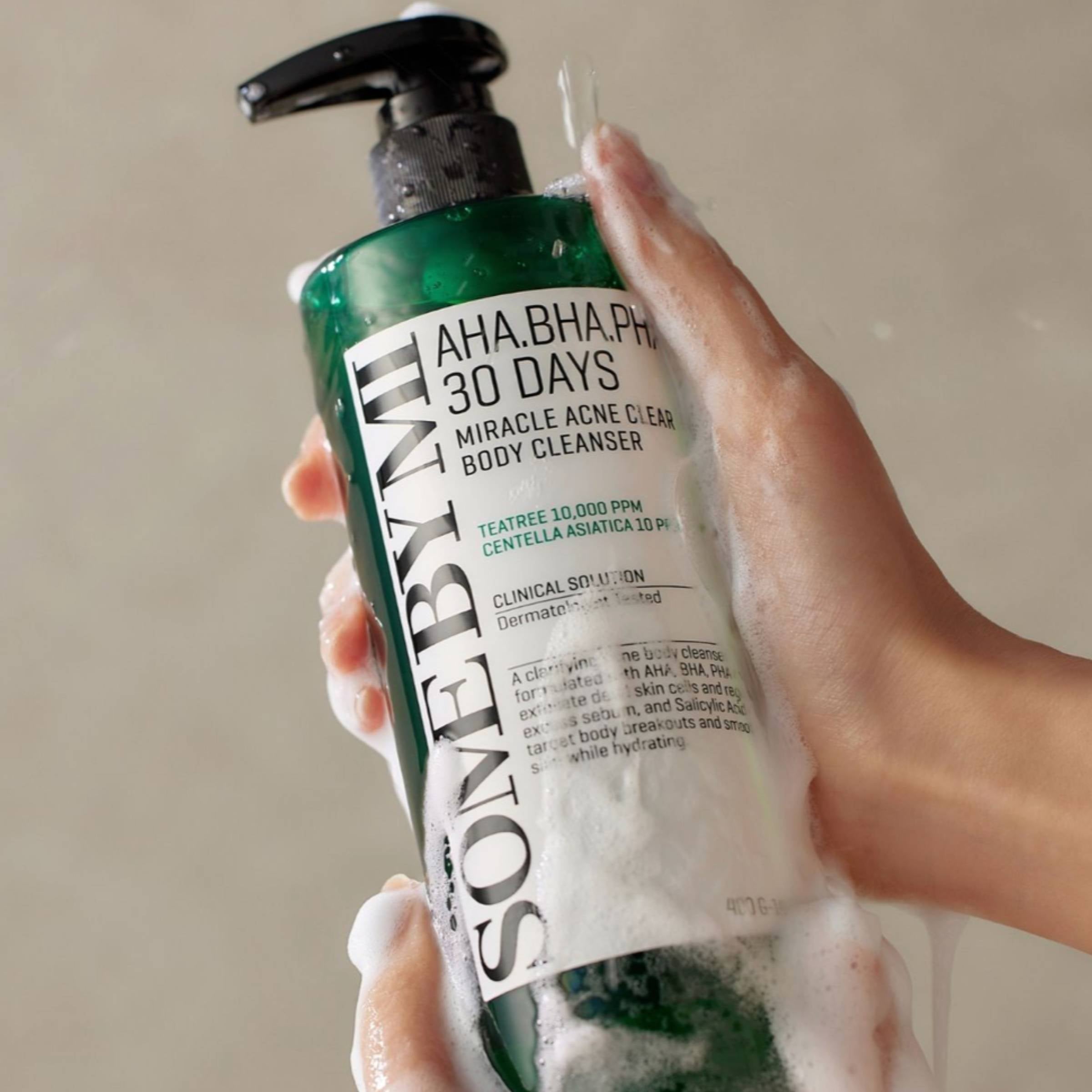 Hand holding a bottle of Some By Mi 30 Days Miracle Acne Clear Body Cleanser with visible foam.