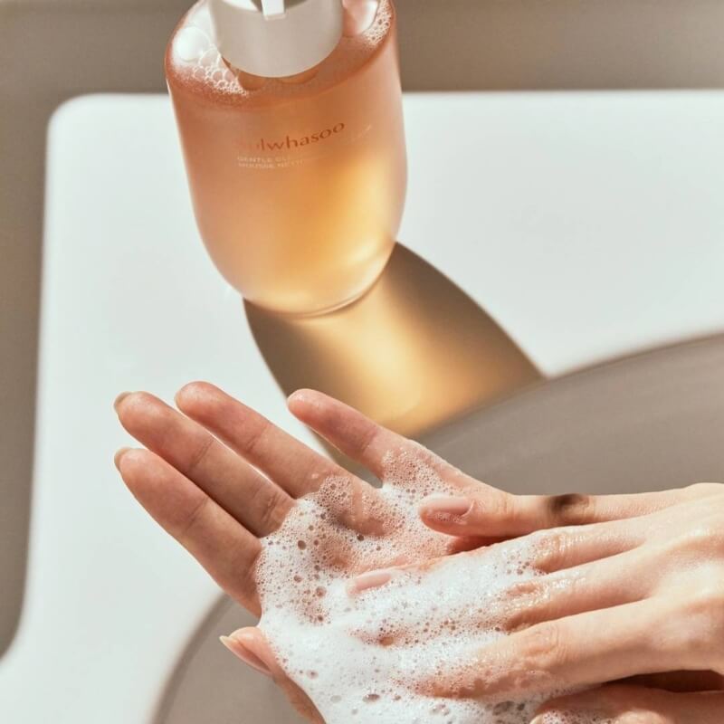 Person applying Sulwhasoo Gentle Foam Cleanser to hands showing the foam with a bottle of Sulwhasoo Gentle Foam Cleanser  in the background.
