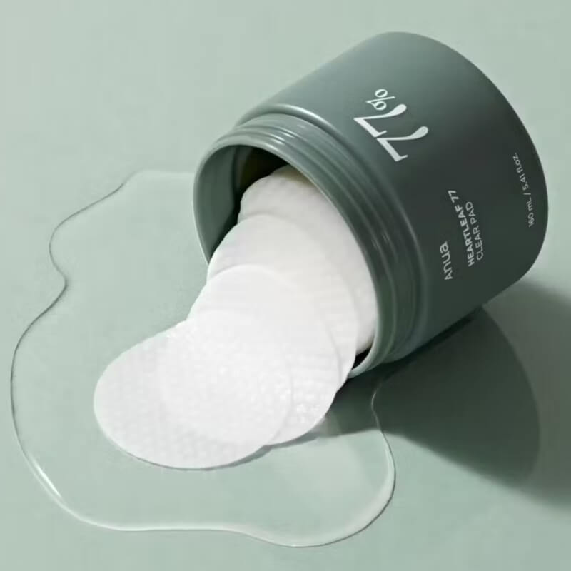 ANUA Heartleaf 77 Clear Pad with white cotton pads on a light green background