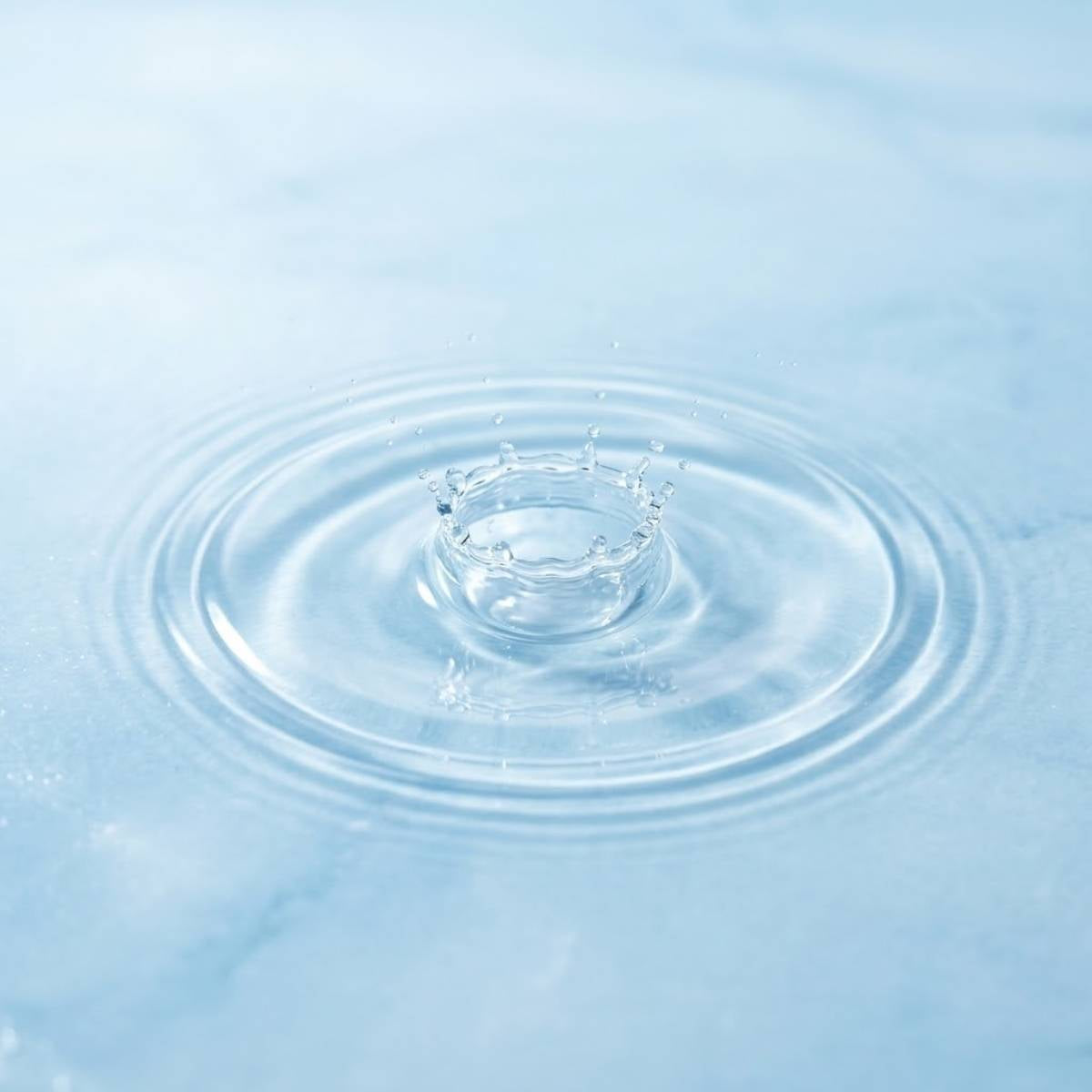 Water droplet splash on blue surface symbolizing hydration for dry and dehydrated skin