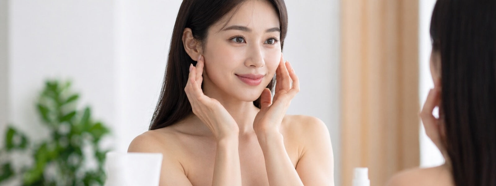 Woman examining her skin in a mirror with a neutral background
