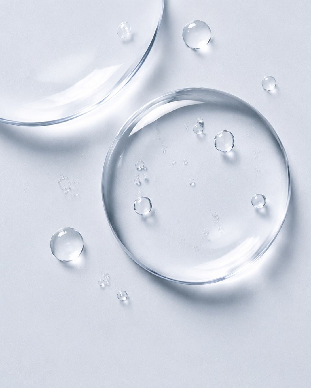 Clear hyaluronic acid droplets on a pale blue background