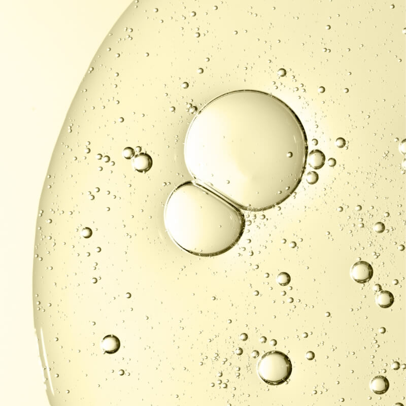 Close-up of retinol oil droplets on a yellowish liquid surface