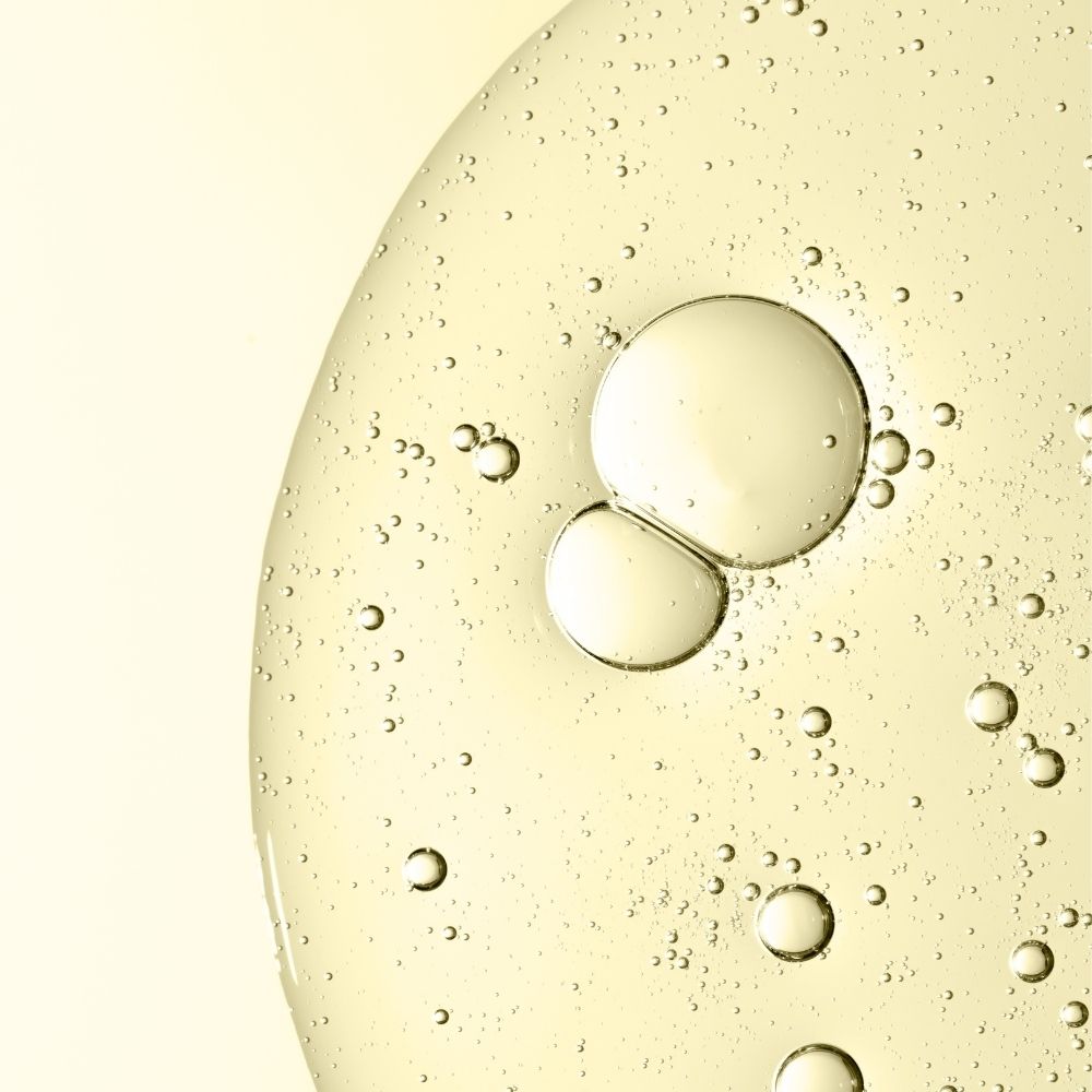 Close-up of retinol oil droplets on a yellowish liquid surface